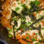 Cheesy Kimchi Fried Rice with spring onion and seaweed sprinkled on top, cooked on a pan or wok from an easy recipe.