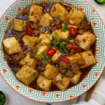 Mapo tofu in dark brown sauce topped with chilli and spring onion, made in a pan with this easy recipe
