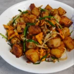 Stir Fried Radish Cake, with crispy skin and condiments, infused with savory goodness!