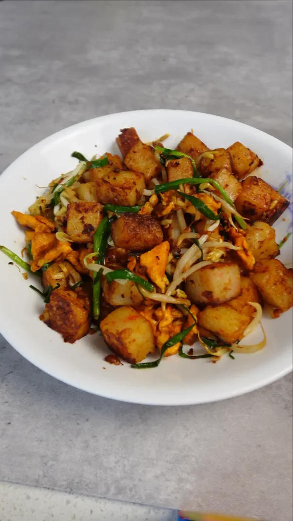 Stir Fried Radish Cake, with crispy skin and condiments, infused with savory goodness!